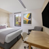 Haberfield Hotel in Sydney guest room with king bed, desk, armchair, and wall-mounted TV