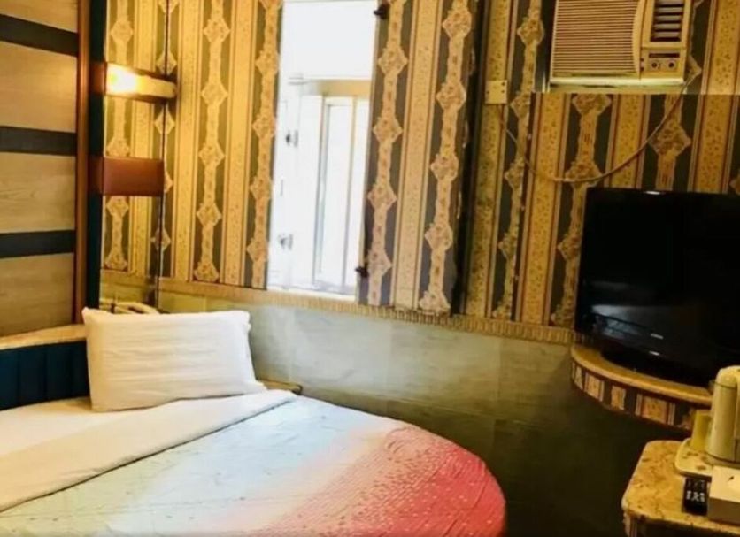 New Style Guest House in Hong Kong room with bed, TV, air conditioner, and patterned wallpaper