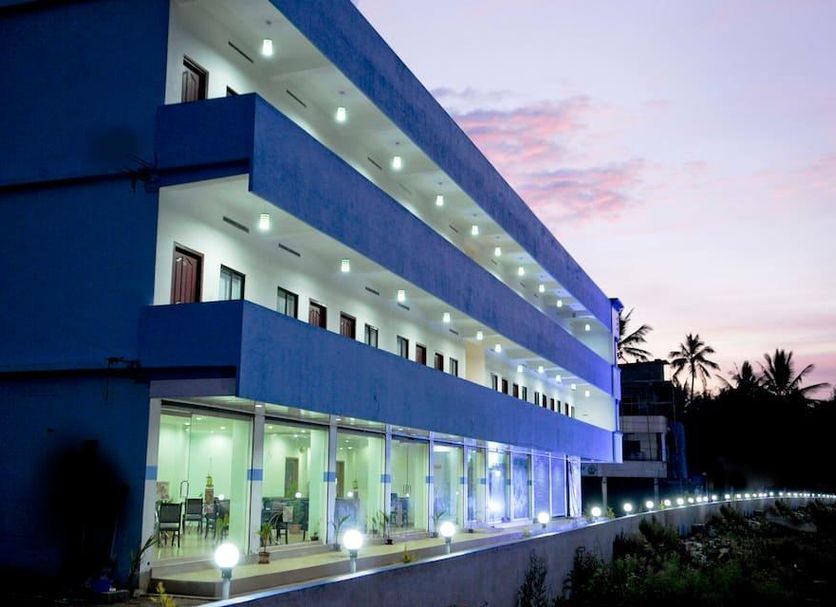 Blooming Paradise hotel in Thekkady at dusk, exterior with lit balconies and glass-fronted ground floor