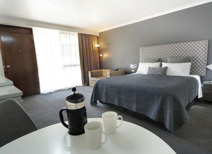 The Heritage Bendigo room with king bed, armchair, desk and round table in Bendigo