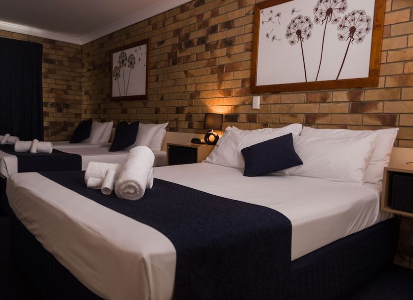 Lancaster Court Motel Brisbane room with two beds, rolled towels, brick wall art and bedside lamps