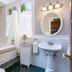 Beaufort House Inn Asheville bathroom with clawfoot tub, pedestal sink, round mirror and window curtains
