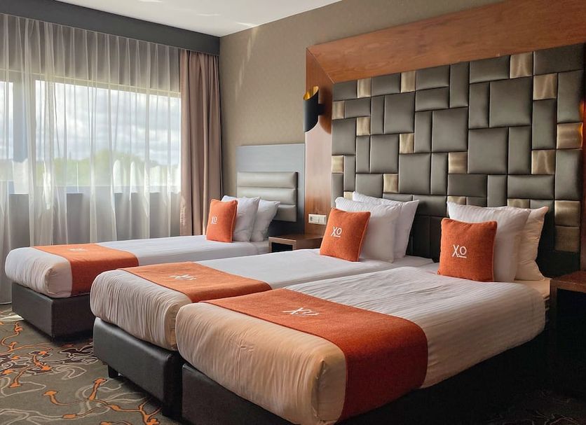 XO Hotels Park West Amsterdam guest room with two beds, orange accents, and large window