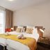 Appart'City Confort Lille Grand Palais bedroom with double bed, yellow throw, and bedside lamps