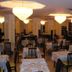 Valdenza in Campegine dining room with set tables, black chairs, and warm ceiling lights