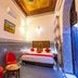 Dar Fes Tresor in Fez: ornate guest room with patterned tile walls, red chairs, and arched doorway