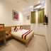Hotel De Ecobiz, Ahmedabad guest room with double bed, wall art, and window curtains