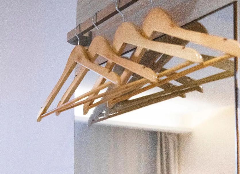 Hanting Hotel Qingdao Chengyang Liuting Airport room mirror with wall-mounted coat hangers and bed reflection