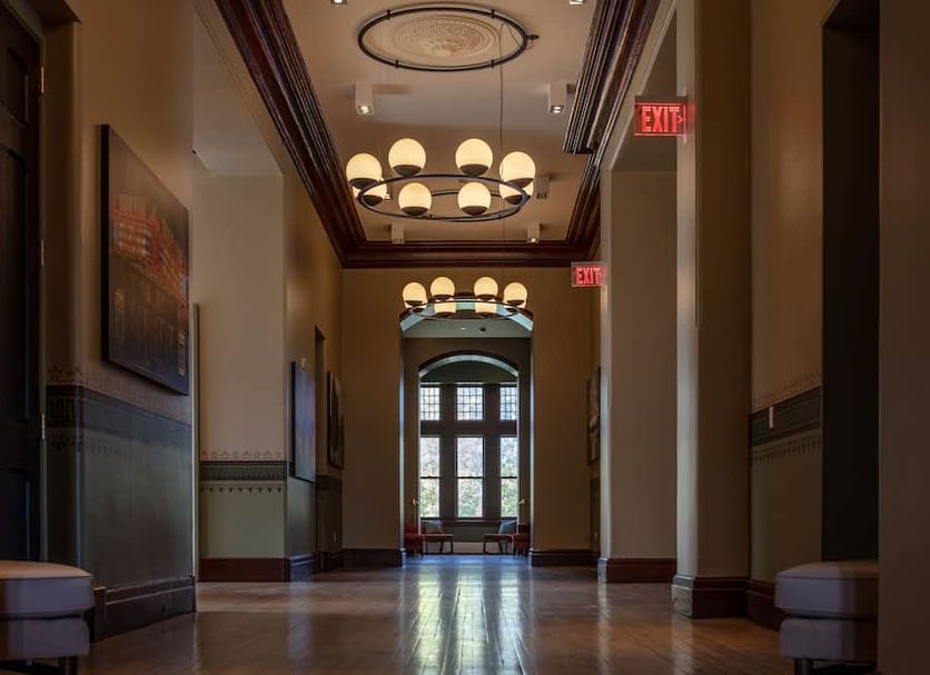 The Richardson Hotel Buffalo hallway with arched windows and hanging globe chandeliers