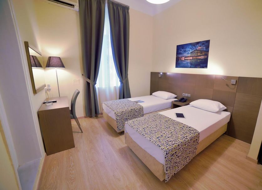 Orestias Kastorias Thessaloniki twin room with two single beds, desk, chair and window with curtains