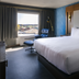 Bally's Baton Rouge Hotel guest room with king bed, lounge chair, and city view window