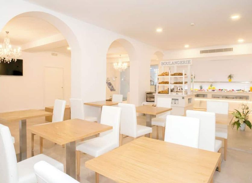 Hotel Playas de Paguera in Peguera dining room with light wood tables, white chairs and arched openings