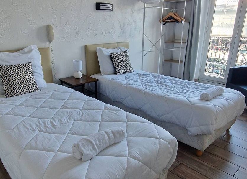 Hôtel du Nord in Cannes room with two twin beds, bedside table, and balcony door