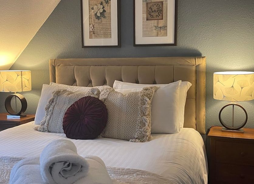 Broadlands Cheltenham guest room with neatly made bed, bedside lamps and framed wall art