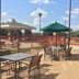The Q Hotel & Suites in Springfield outdoor patio with tables, chairs, umbrellas, and fenced pool area