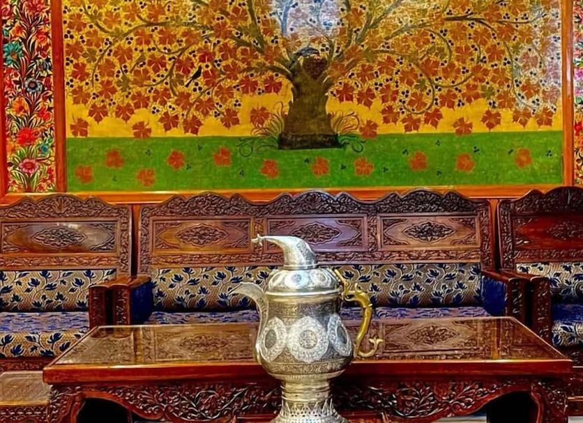 Hotel Centre Point in Srinagar with ornate carved seating, table, and colorful tree mural
