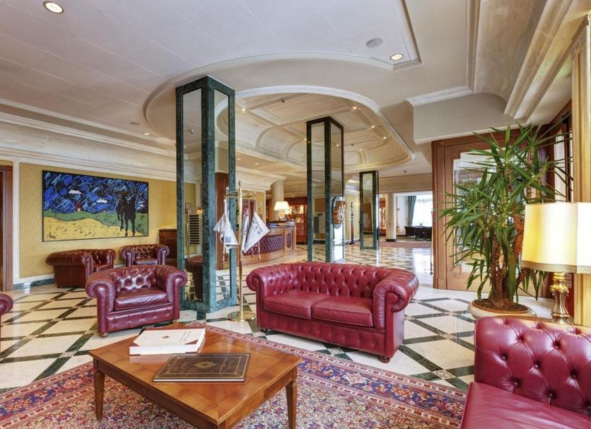 Borgo Palace Hotel in Sansepolcro lobby with red leather sofas, patterned tile floor, and glass columns