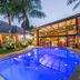 Sunrock Guesthouse in Kempton Park with a lit outdoor pool, palm trees, and glass-fronted building at dusk