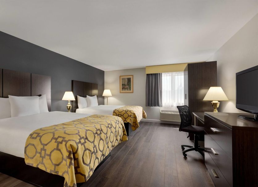Baymont by Wyndham Branford/New Haven guest room with two beds, desk, TV and window view in Branford