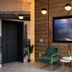 Hotel Mirage Brooklyn lobby with green chairs, wall-mounted TV, and wood-paneled walls in Brooklyn