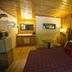 Black Bear Lodge Motel in Slade guest room with plaid bed, wood-paneled walls, and sitting area