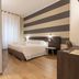 La Loggia de' Banchi, La Spezia: modern guest room with striped accent wall, bed, and bathroom doorway