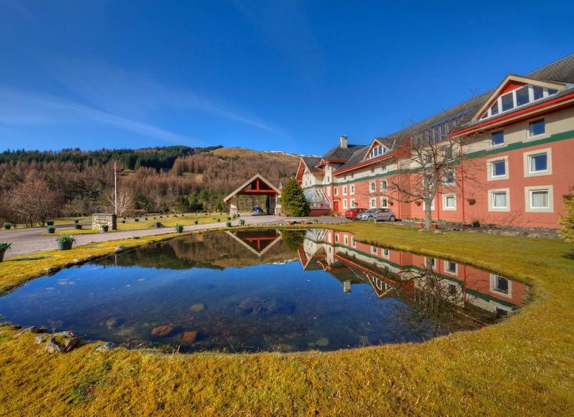 Muthu Ben Doran Hotel in Crianlarich with a pond reflecting the hotel and hillside scenery