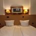 Yeti City Hotel Saarbrücken guest room with twin beds, wall lamps and framed artwork