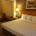 Wingate by Wyndham Coon Rapids guest room with king bed, armchair, and bedside lamp