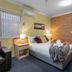 Park Beach Resort Motel room in Coffs Harbour with bed, armchair, bedside lamps and brick accent wall