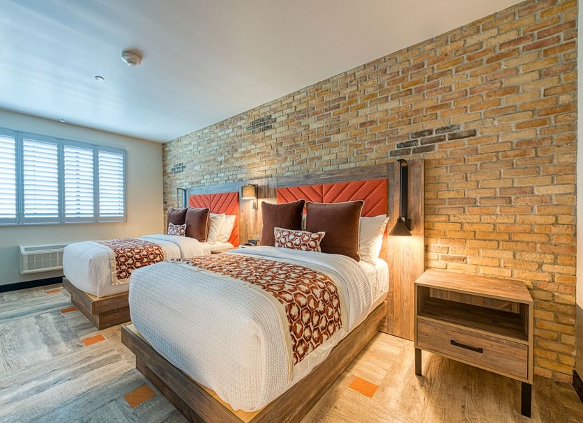 Hotel Lexen Newhall in Newhall guest room with two twin beds, exposed brick wall and window shutters
