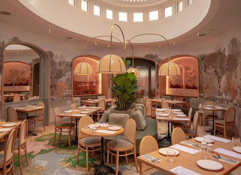 Miss Fuller in Paris dining room with skylit ceiling, mural walls, and set tables
