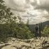 Hotel Heikenberg in Bad Lauterberg with a hiker overlooking forested mountains under cloudy skies