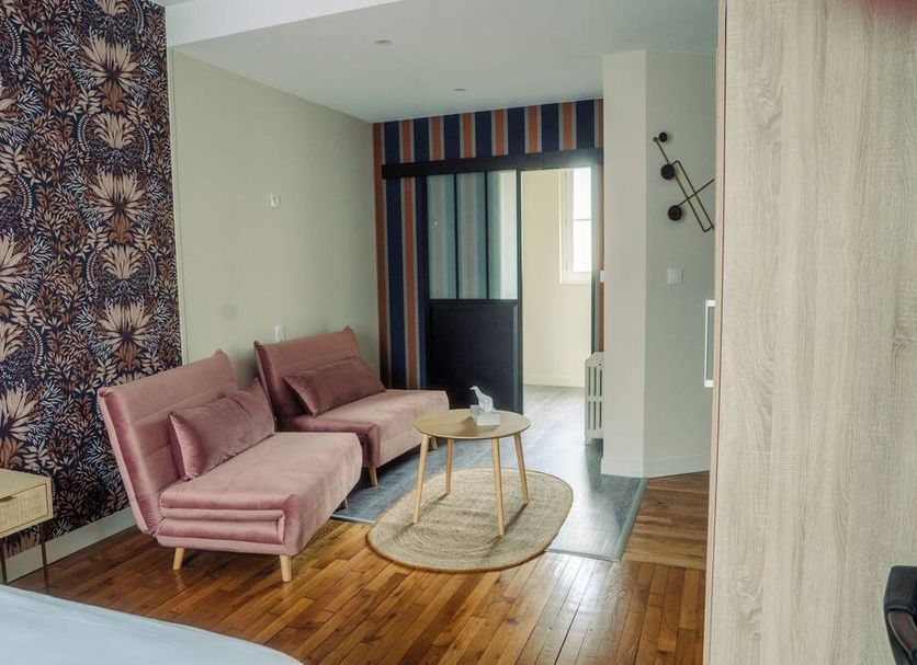 Logis -Hotel & Restaurant De La Place in Seulline: stylish lounge with pink sectional sofa and wood floors