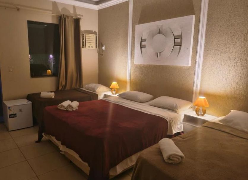 Pousada Bon Vivant in Cabo Frio, simple guest room with three beds and bedside lamps