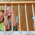 Dancamps Kolding children peeking through wooden cabin railing