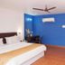 Le Pearl Goa Resort & Spa in Vagator bedroom with blue accent wall, balcony door and ceiling fan