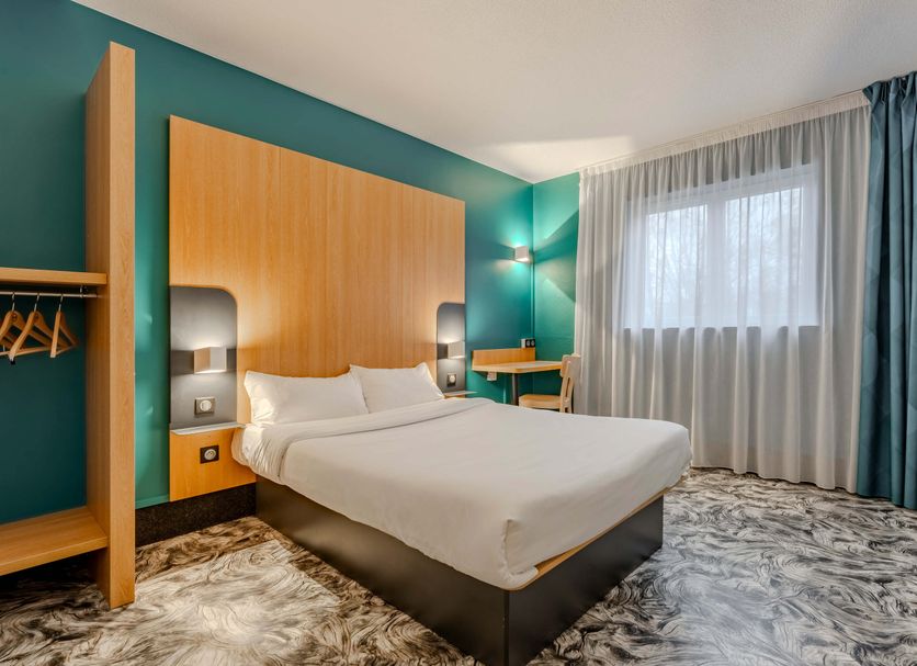 B&B HOTEL Maubeuge-Louvroil room with double bed, teal walls and large window in Louvroil