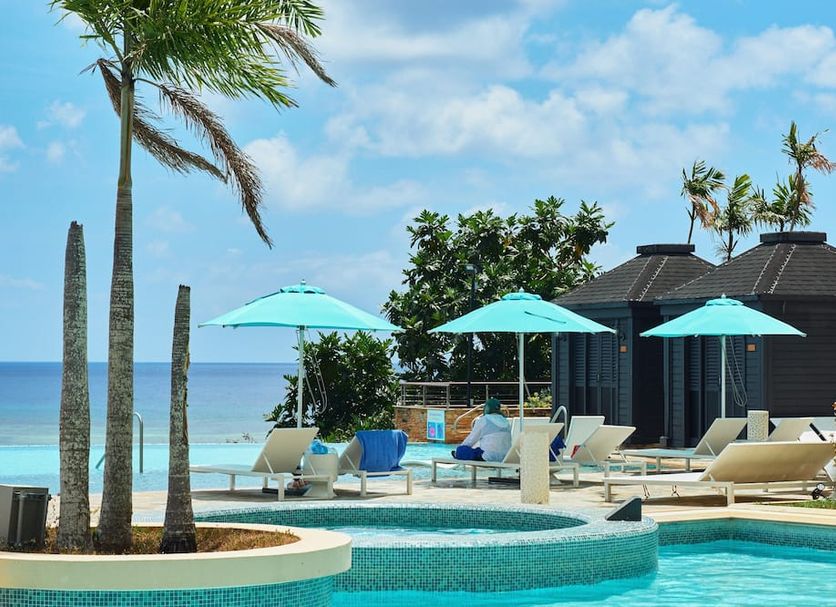 Lotte Hotel Guam in Tamuning with oceanfront pool, lounge chairs, turquoise umbrellas and sea view