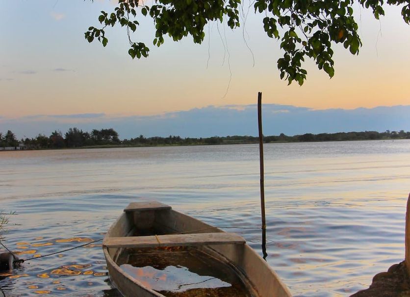 Hotel Gran Palmeiras in Playa de Chachalacas with a small boat on a calm waterfront at sunset