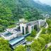 Tian Xing Hotel in Chongqing beside lush mountains and a river, with modern buildings and green landscaping