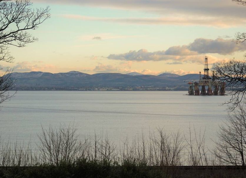 Kingswood Hotel in Burntisland with tranquil bay views, distant hills, and offshore oil rig at sunset