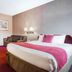 Ramada by Wyndham 100 Mile House guest room with king bed, desk, sofa, and wall lamps