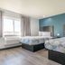 Studio 6 Suites Perris, CA room with two beds, window, and blue accent wall