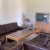 Grindsted Aktiv Camping lounge with brown leather sofas, wooden coffee table, TV and side lamp in Grindsted