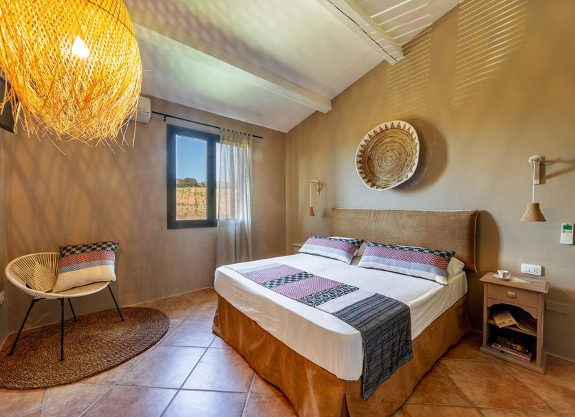 Borgo di Campagna in Golfo Aranci: guest room with double bed, window, chair, and warm decor