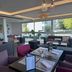ibis Styles Ouistreham lounge with seating, dining tables, and large windows overlooking greenery in Ouistreham