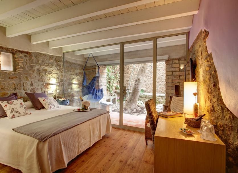 La Freixera in Solsona guest room with stone walls, bed, desk and sliding glass doors to a patio