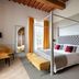 Relais Villa Grazianella Una Esperienze room in Acquaviva with canopy bed, bench and window seating