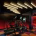 The Cura Hotel Kensington London gym with treadmills, elliptical and red-lit mirrored corridor